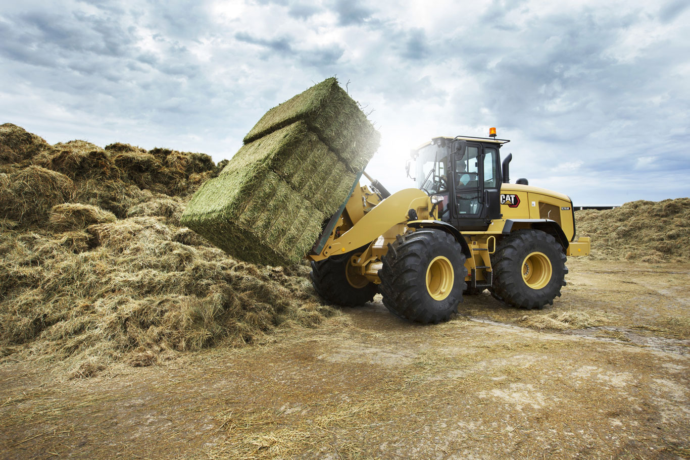 Cat AG tractor lifting hay bale